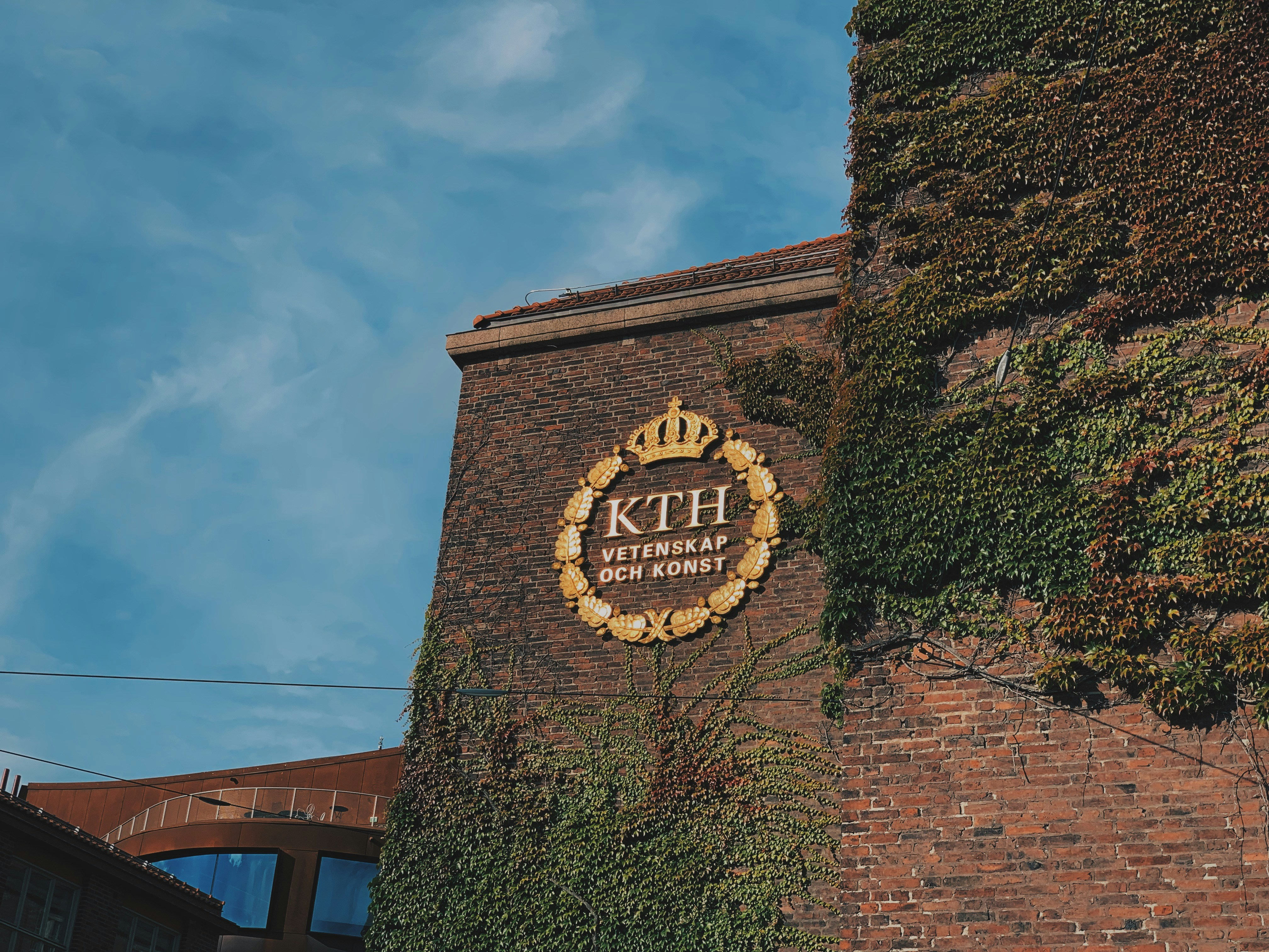 KTH Royal Institute of Technology crest on an ivy-covered brick building
